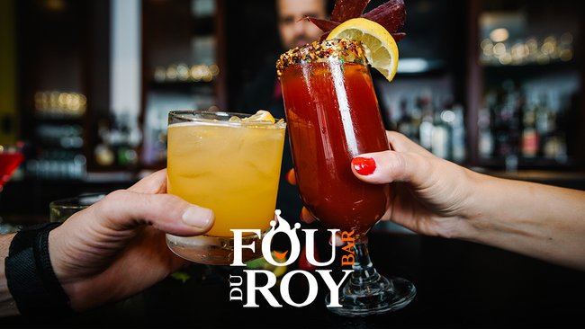 Two colourful cocktail glasses raised for a toast, one containing a yellow drink on the rocks, the other a red cocktail garnished with lemon and spices, in front of an elegant bar. Bar le Fou du Roy logo in the centre, inviting you to enjoy a convivial evening with a variety of cocktails.