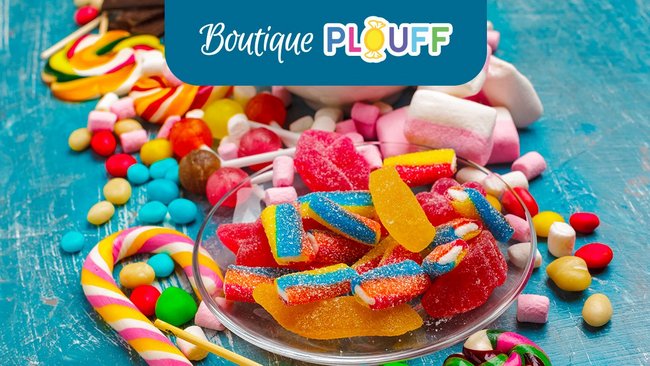 A colourful variety of sweets and candies neatly arranged on a table, with a sign saying ‘Boutique Plouff’ at the top. The Boutique Plouff at L'Hôtel Québec offers a selection of perfect delights.