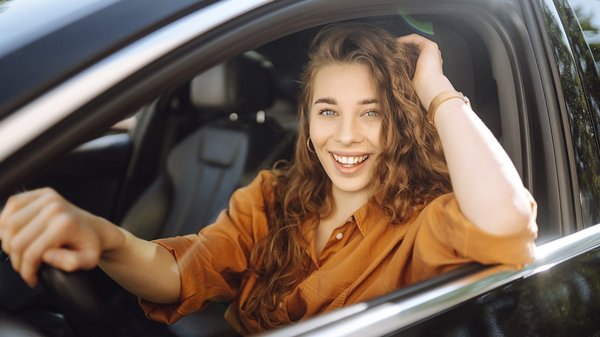 Femme souriante assise dans une voiture, symbolisant la promotion spéciale de rabais pour les membres du CAA.