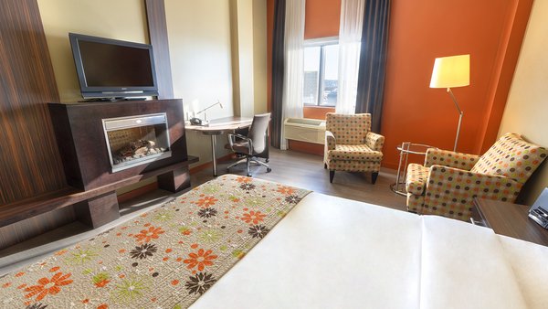 Trendy hotel room with king-size bed, cozy fireplace and TV for a pleasant stay at Hotel Must