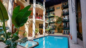 Interior view of Hotel Plaza with a pool surrounded by columns, balconies, and tropical vegetation.