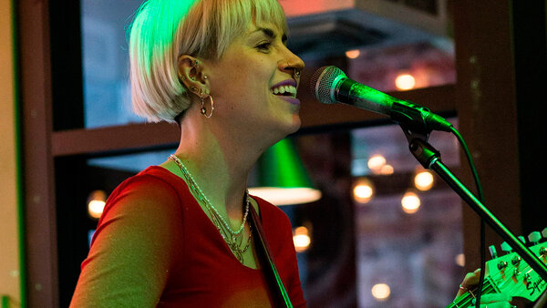 Cassandre Picard smiles, plays guitar and sings during a musical performance at the Hôtel Palace.