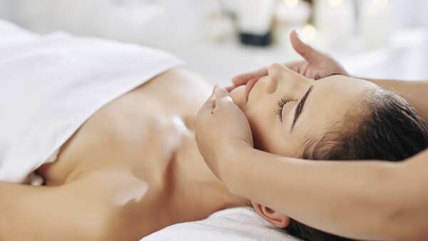 A woman receiving a relaxing facial massage, representing the Zen package at Quebec Inn, focused on comfort and well-being.